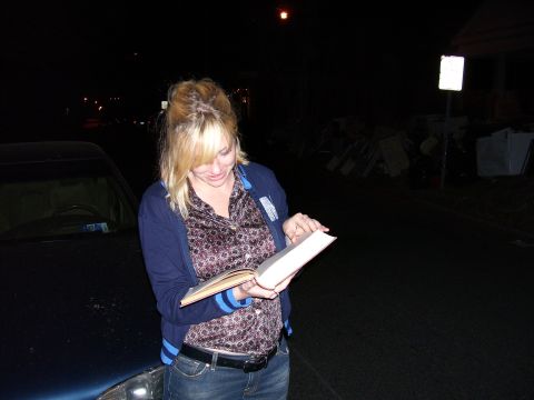 1992 Ford Bronco - A woman reads a book while standing next to a car in the dark.
