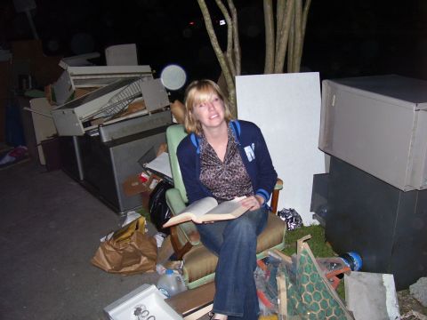 1992 Ford Bronco - A woman sits in a chair reading a book, surrounded by various discarded items and appliances.