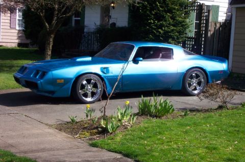 1979 Pontiac Trans Am - A blue coupe with custom wheels is parked in front of a house.