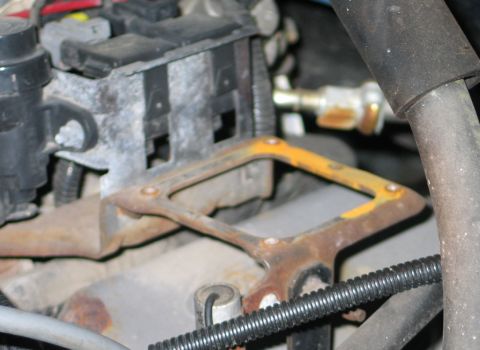 1994 Ford Bronco - Close-up of a rusty engine part with visible electrical components and hoses.