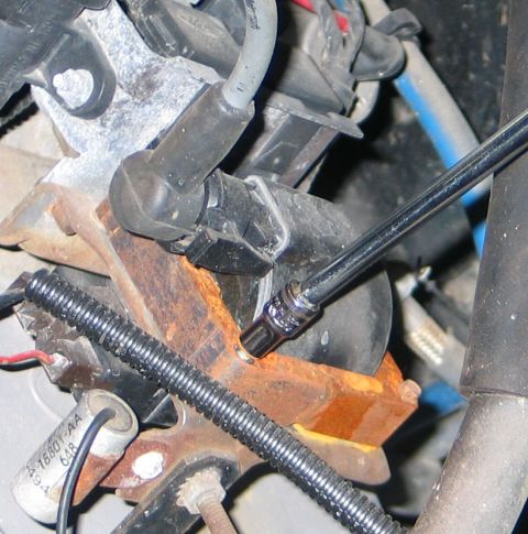 1994 Ford Bronco - A socket wrench is used on a rusty component near the ignition coil of an engine.