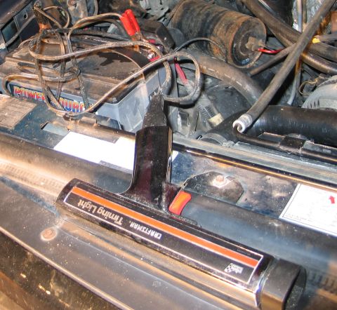 1994 Ford Bronco - A Craftsman timing light is positioned over the engine bay, near a car battery and various hoses.