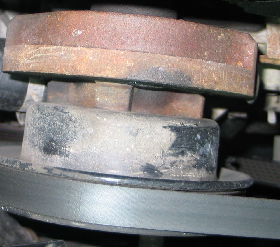 Close-up of rusty stacked pulleys with a black drive belt below