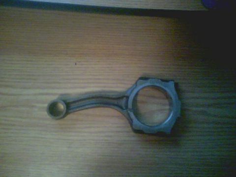 1996 Ford Probe - A single connecting rod is shown lying on a wooden surface.