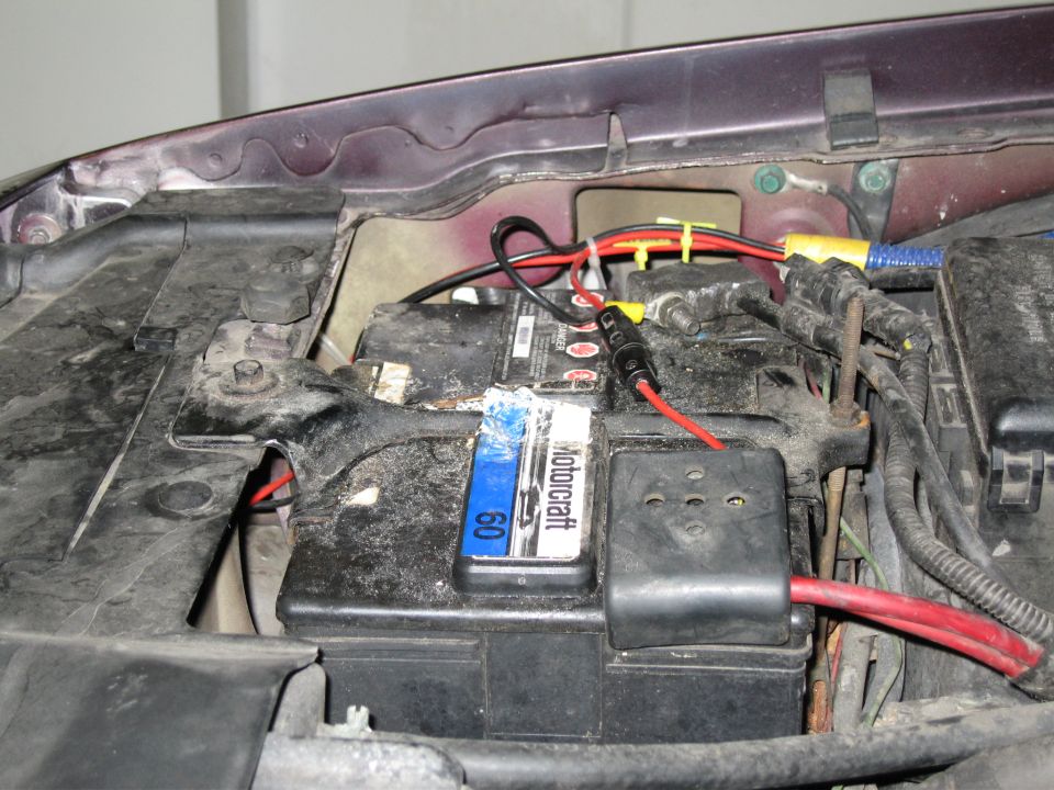 Car battery with red and black wires connected, under the hood