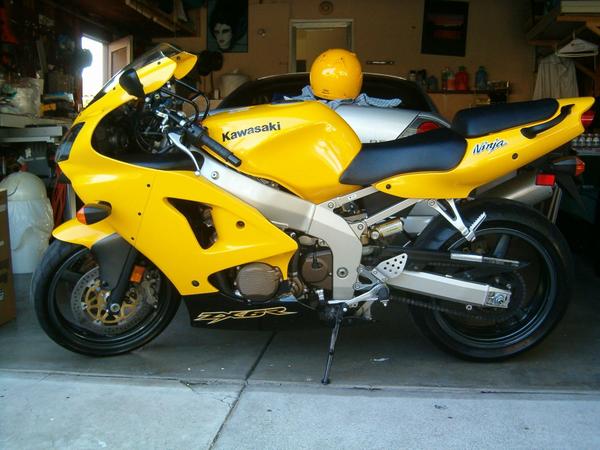 Yellow Kawasaki Ninja ZX-7R sportbike on kickstand in a garage with helmet on tail