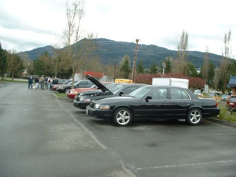 1999 Ford Crown Victoria - A line of sedans are parked in a lot, with a black sedan prominently in the foreground. The vehicle appears to be a 1998 model.