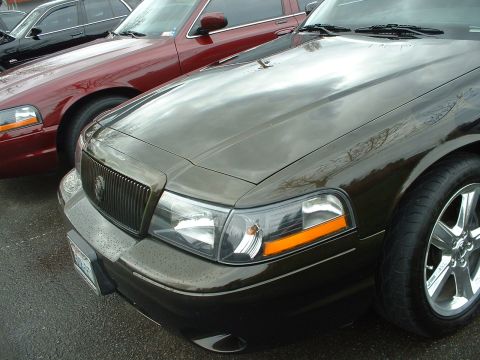 1999 Ford Crown Victoria - A dark metallic 2000 Ford Crown Victoria is parked next to a maroon sedan, showing its front quarter profile.