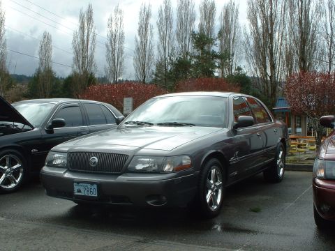1999 Ford Crown Victoria - A Mercury Grand Marquis is parked in a lot with other vehicles visible.