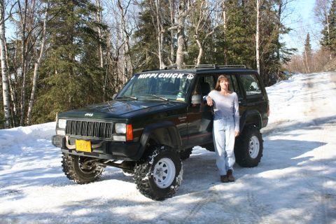 1995 Jeep Cherokee - A 1995 Jeep Cherokee is parked in the snow, with a woman standing beside it and a 'HIPPI CHICK' sticker on the windshield.