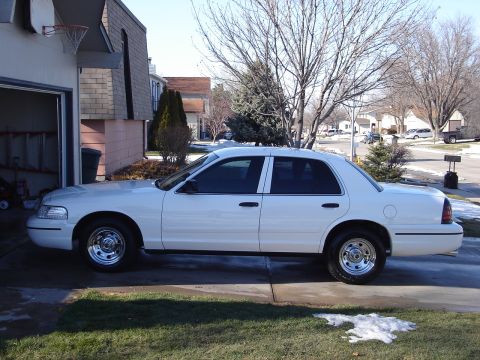 2000 Ford Crown Victoria - A white 2000 Ford Crown Victoria is parked in a driveway on a sunny day.