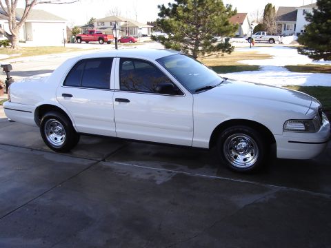 2000 Ford Crown Victoria - White 2000 Ford Crown Victoria parked on a driveway with houses and trees in the background.