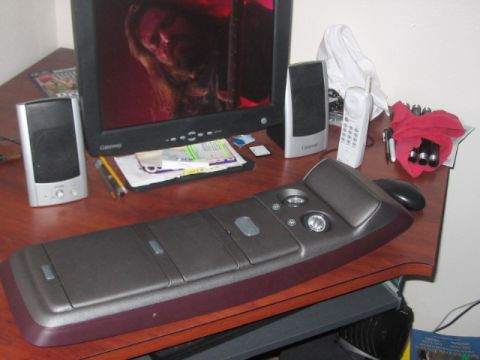 1991 Ford Bronco - A cluttered desk scene a computer monitor, speakers, a cordless telephone, and an unusual ergonomic keyboard.
