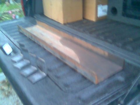 1992 Ford Bronco - A long length of rusty steel angle iron and a row of small cut steel plates or brackets laid out in a bedliner-coated pickup bed, with card…