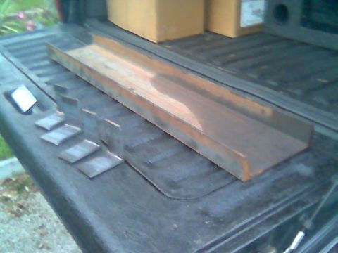 1992 Ford Bronco - Metal winch part and brackets are laid out on the bed of a truck.