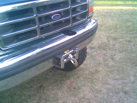 1992 Ford Bronco - Close-up of the front of a light-colored Ford truck showing the chrome grille with blue Ford oval, chrome bumper, and a receiver-mounted hi…