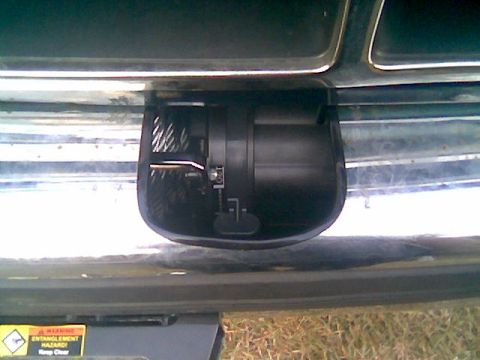1992 Ford Bronco - Close-up of a black winch mounted behind the chrome front bumper of a dark truck, showing the drum, motor housing and fairlead cutout in th…