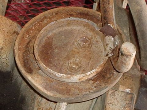 1990 Ford Bronco - This image shows a heavily rusted suspension component, likely a coil spring, with visible bolts and mounting brackets.