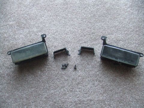 1995 Ford Probe - Two fog lights and associated hardware are laid out on a carpeted floor.