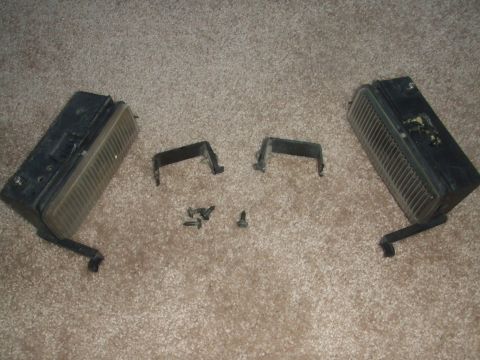 1995 Ford Probe - Two car headlights and mounting hardware laid out on a carpeted surface.