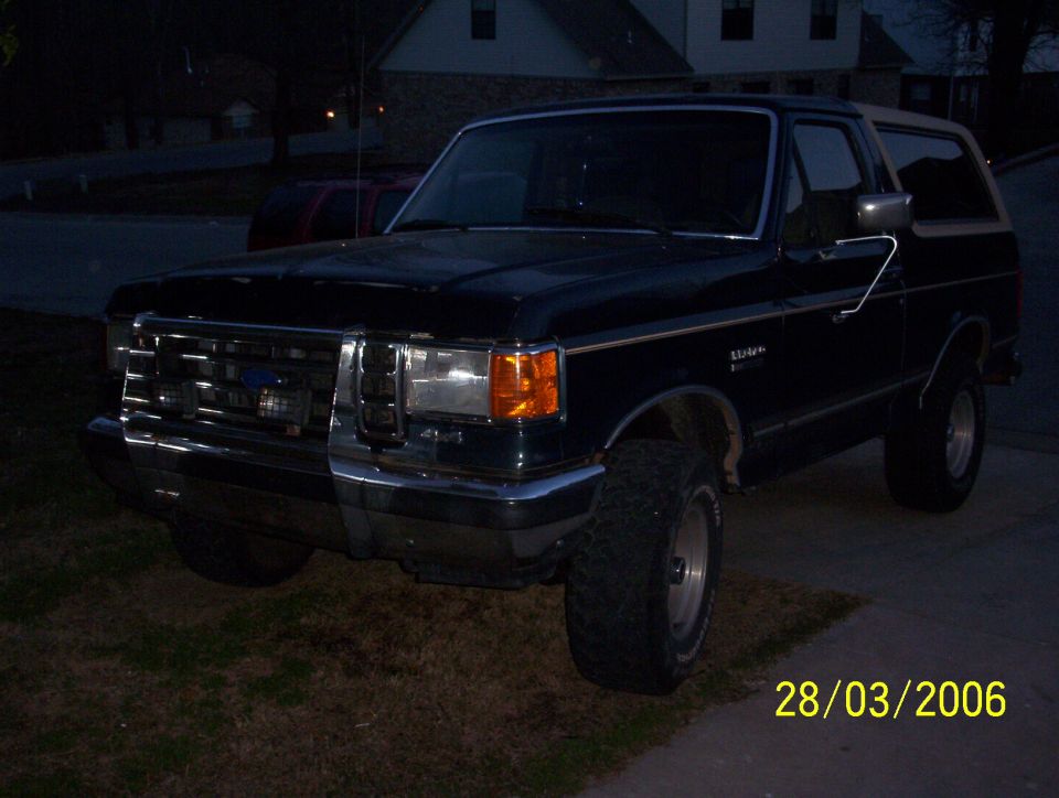 Black Ford Bronco parked outside at dusk. It has a tan top and off-road tires