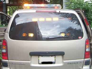 1998 Ford Crown Victoria - Rear view of a tan/gold Chevrolet Venture minivan fitted with an amber-and-clear roof light bar and a row of four amber deck lights mounted…