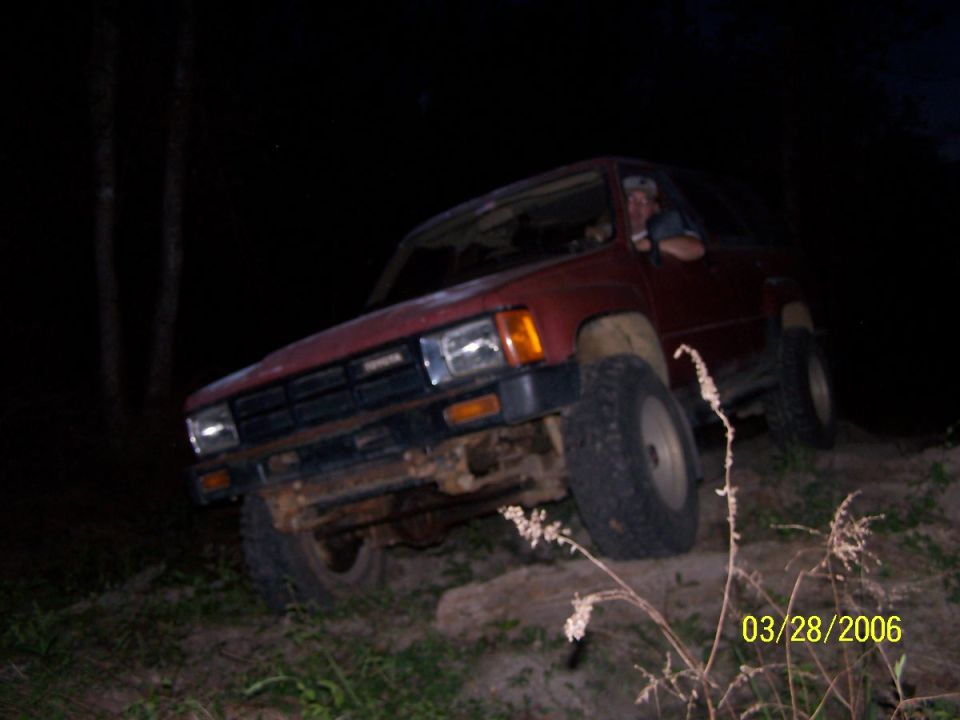 Red 1984 Toyota 4Runner on uneven terrain at night, front 3/4 view