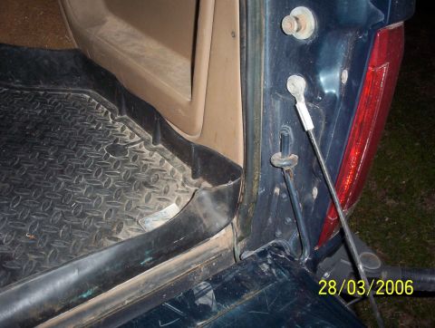 1991 Ford Bronco - Close-up view of the rear cargo area and tailgate hinge mechanism of a dark blue SUV.