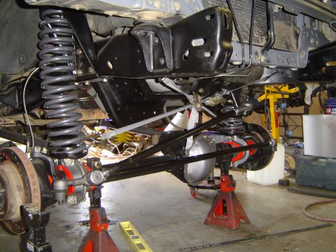 1989 Ford Bronco - Close-up of vehicle suspension and axle work in progress, supported by jack stands.