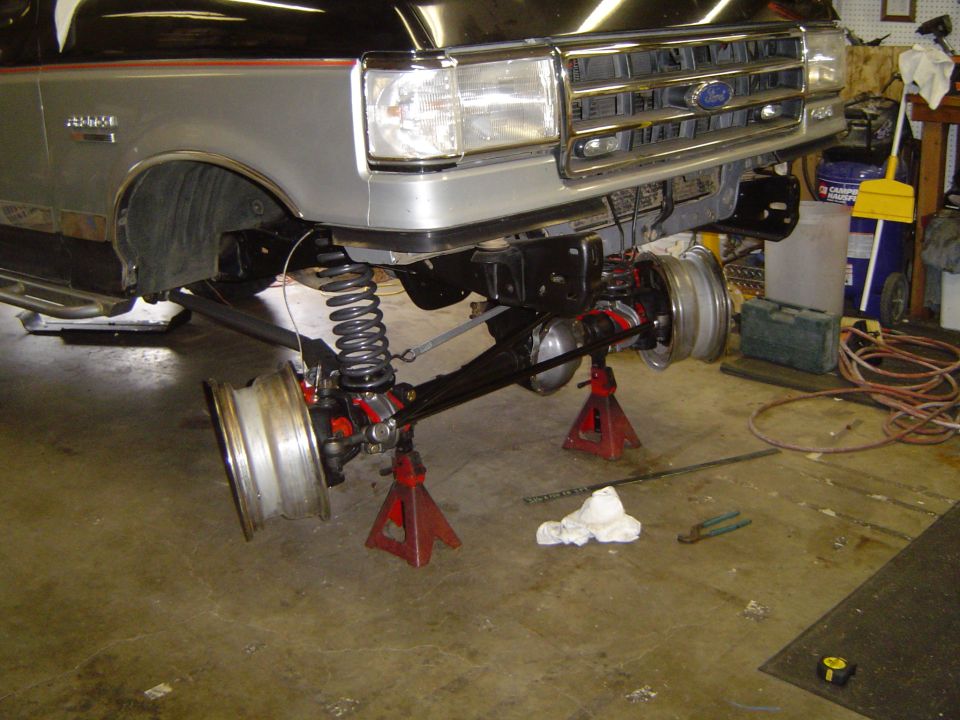 Silver Ford Bronco on jack stands showing solid front axle and coil spring suspension