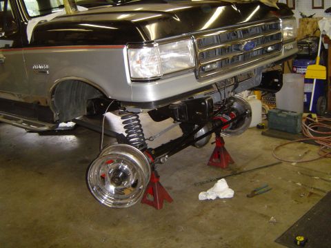 1989 Ford Bronco - Front end of a Ford truck, possibly from the late 1980s, is elevated on jack stands for maintenance.