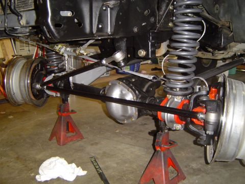 1989 Ford Bronco - The front axle and suspension of a 1989 Ford Bronco are visible, supported by jack stands during installation.