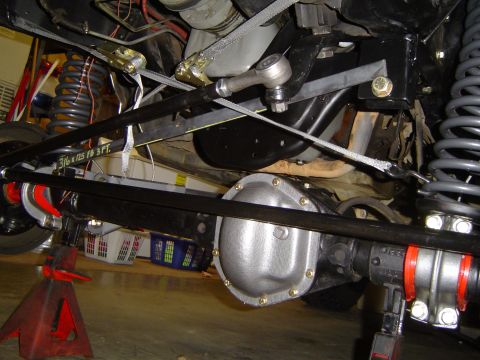 1989 Ford Bronco - Close-up of a vehicle's undercarriage, focusing on the differential and suspension system, with visible tie rod and securing straps.