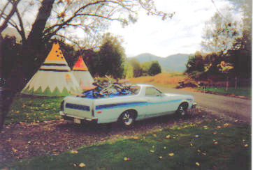 2002 Ford Crown Victoria - A light blue Ford Ranchero parked outdoors with bicycles loaded in the bed.