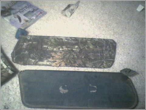 1981 Ford Bronco - Two sun visors are laid out on a floor, one with a camouflage pattern and the other solid black.