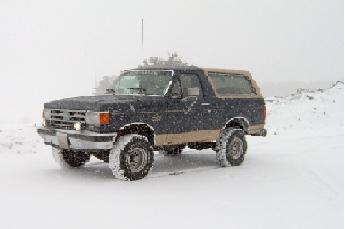 1991 Ford Bronco - A 1991 Ford Bronco drives through a snowy landscape.