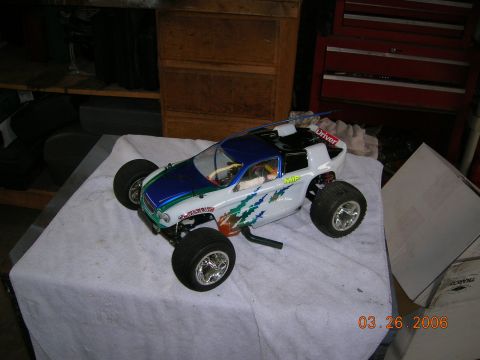 1985 Ford Bronco - A remote control car with a white body, blue hood, and green graphics is displayed on a table.