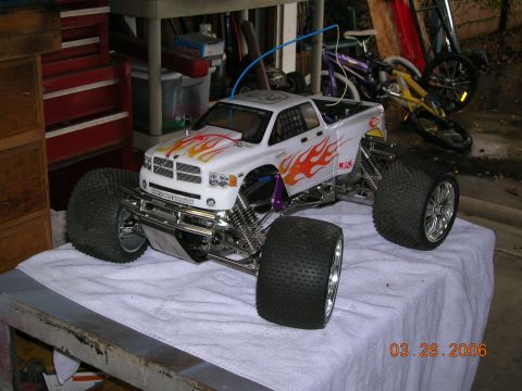 1985 Ford Bronco - A remote control truck with flame graphics is displayed on a towel, with bicycles in the background.
