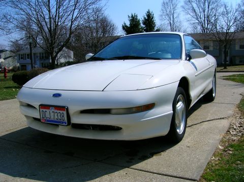 1997 Ford Probe - A white 1997 Ford Probe is parked on a driveway in front of a residential home.