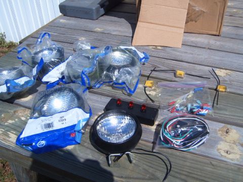 1988 Ford Bronco - A collection of automotive lighting parts and accessories are spread out on a weathered wooden deck.
