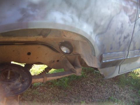 1988 Ford Bronco - A rock light is visible mounted on the frame of a vehicle, near the rear wheel well and suspension components.