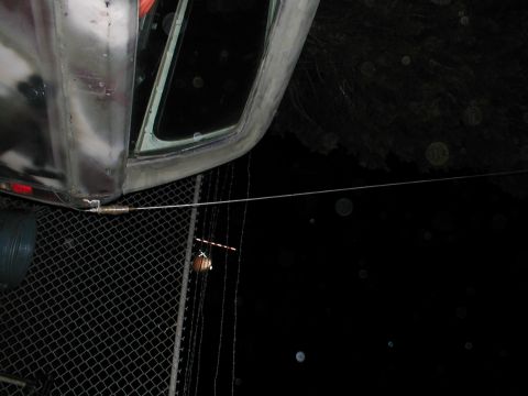 1979 Ford Bronco - A close-up view of a vehicle's side door and window, with a wire extending across a fence in the foreground.