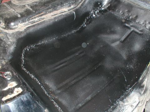 1979 Ford Bronco - Close-up view of the underbody of a vehicle, showing areas of black spray paint and some rust.