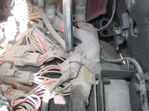 1991 Ford Bronco - A complex network of wires and connectors, obscured by dust and tape, is visible in this close-up.
