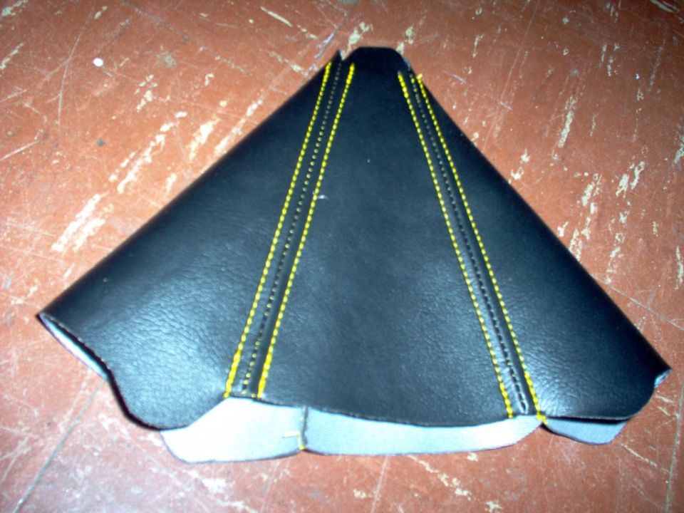 Black leather shift boot with yellow stitching on a worn surface
