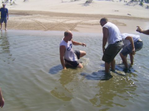 1985 Ford Bronco - Several people are in the water near a sandy shore, with one person partially submerged.