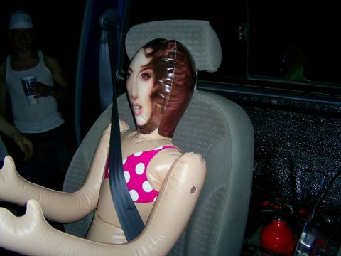 1985 Ford Bronco - An inflatable doll is buckled into the passenger seat of a vehicle, with a person visible in the background.