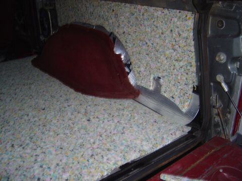 1978 Ford Bronco - Sound deadening material installed in the interior of a vehicle, showing a red carpeted section and foil backing.