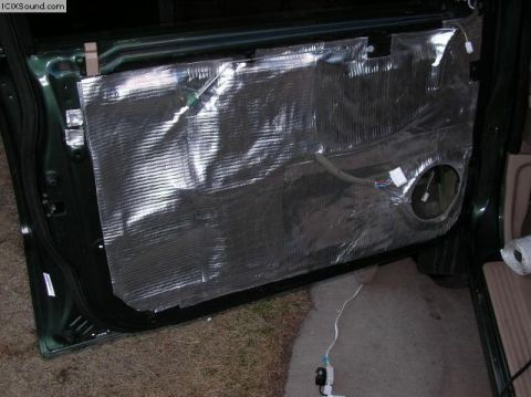1978 Ford Bronco - The interior of a car door is covered in sound deadening material, revealing wiring and a speaker opening.