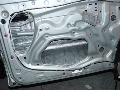 1978 Ford Bronco - Close-up view of a vehicle's interior door panel, showing the application of silver sound deadening material.